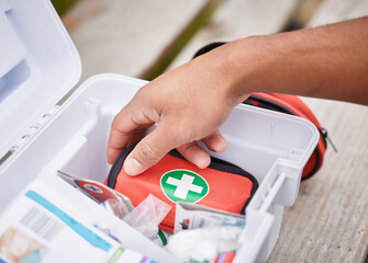 Everything he needs to treat your injuries. High angle shot of an unrecognizable male paramedic looking in his first aid kit while standing outside.