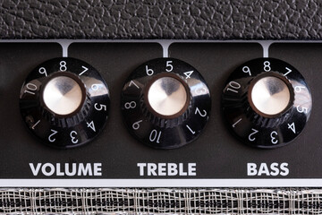 detail of the volume, treble and bass control knobs of a guitar amplifier, equalization dials close...