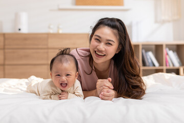 New asian mom Newborn baby laying on stomach developing neck control.tummy time for strengthen baby neck and shoulder muscles.Cute infant lying crawling with mother happy and fun.Tummy Time Concept