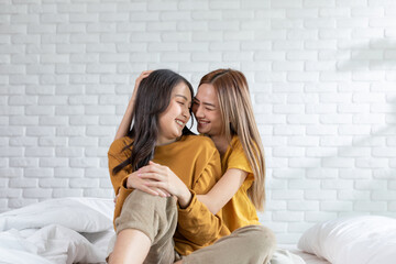 Beautiful two female LGBT lesbian embracing and looking together with love and romance on bed.Positive mood and moment of LGBTQ lesbian lying on white bed relax and comfort.LGBTQ Lifestyle Concept