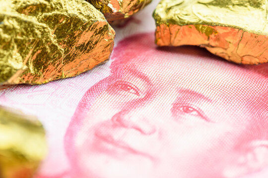 Precious metals and currency investment concept : Gold colored iron ore on a China yuan money, depicting investing in gold market to diversify risk through the use of futures contract and derivatives.