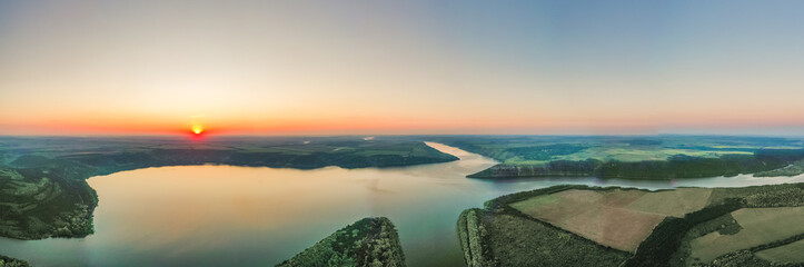 Obraz premium Magnificent aerial view of the Dniester River with picturesque banks during dawn. Bakota National Natural Park, Podolskie Tovtry, Ukraine. Beautiful view from a flying drone.