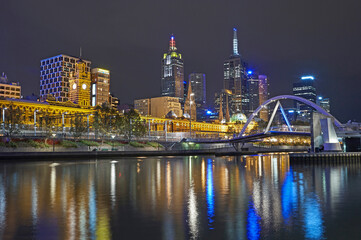 Fototapeta na wymiar Southgate Footbridge spanning the River Yarra in Melbourne illuminated at night with financial district