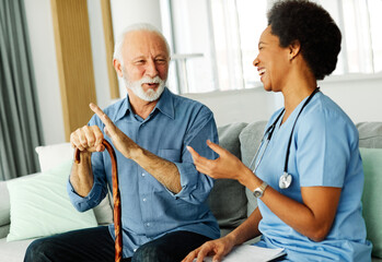 Obraz premium nurse doctor senior care caregiver help assistence retirement home nursing elderly woman man health support african american black walking cane