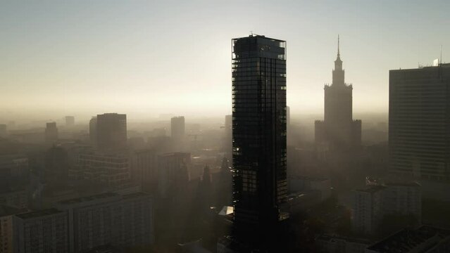 Modern business districtcity glass skyscrapers drone zoom in close to the buildings. Skyscraper in the big city top view during the sunrise when first sun rays are going through the glass windows.