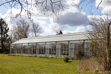 Fototapeta na wymiar Glass greenhouse in early spring against a cloudy sky. High quality photo