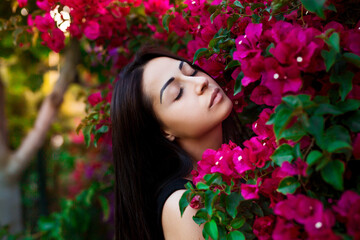 Fototapeta premium Close up portrait of a beautiful girl near colorful flowers. Pretty tender young woman model looking at camera.