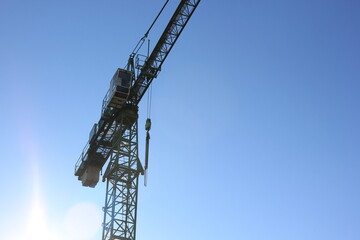 Silhouette of the construction crane against a blue sky