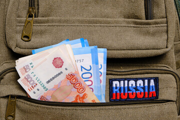 Obraz premium Paper banknotes Russian ruble in denominations two and five thousand pocket backpack with inscription Russia.