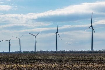 Wind turbines on farmland against a clear sky early spring.
