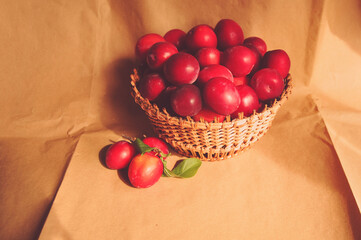 
Composite photo of red plums in a basket standing on a table. Craft paper. Healthy eating. Fruit.
