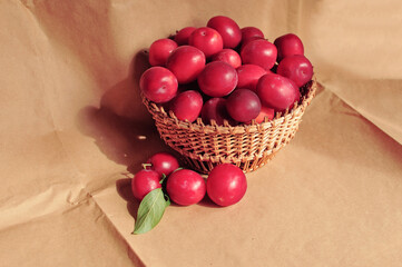 Composite photo of red plums in a basket standing on a table. Craft paper. Healthy eating. Fruit.