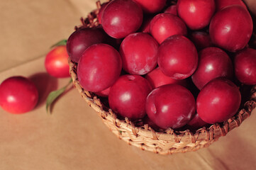 Composite photo of red plums in a basket standing on a table. Craft paper. Healthy eating. Fruit.