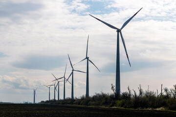  Wind turbines on farmland against a clear sky early spring.