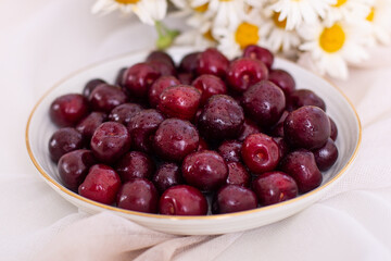 Sweet cherries on golden plate with chamomile