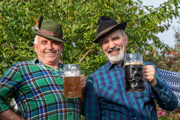 Senior men with beer mugs with Bavarian beer in Tyrolean hats celebrating a beer festival in...