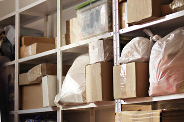 Storage of boxes and crates on shelves. Warehouse with shelving in a garage or utility room. Blurred wall background