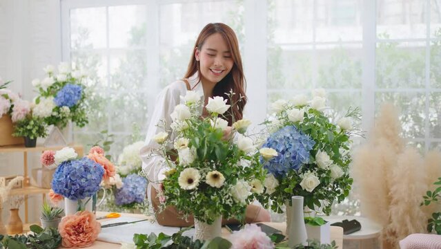 Small business and New market concept.Young florist female making bouquet of roses at workplace.woman artist working in flower shop studio.Floristry showing masterclass on creating flower arrangement.
