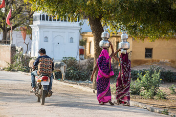 Two women carrying jars on their head, in Vrindavan, UP - Powered by Adobe