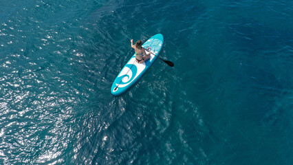 Aerial drone photo of fit unidentified woman paddling on a SUP board or Stand Up Paddle board in...