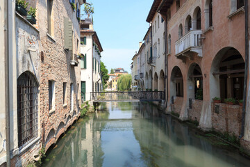 Fototapeta na wymiar Canal Canale dei Buranelli with houses and bridge in Treviso, Italy