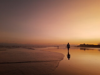 Fototapeta na wymiar Pessoa andando no por do Sol na praia.