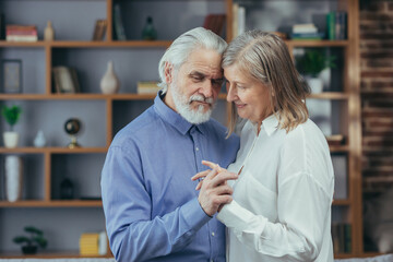 Obraz premium Happy senior couple husband and wife have fun dancing at home, having a good time