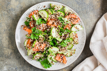 Appetizing salad of cucumbers, tomatoes, a mixture of quinoa and parsley on a plate on the table.