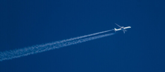 Commercial Airliner at High Altitude with Contrails in a Deep, Blue Sky