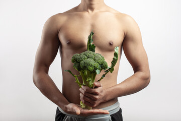 young sports athletic man holding a broccoli on his hand