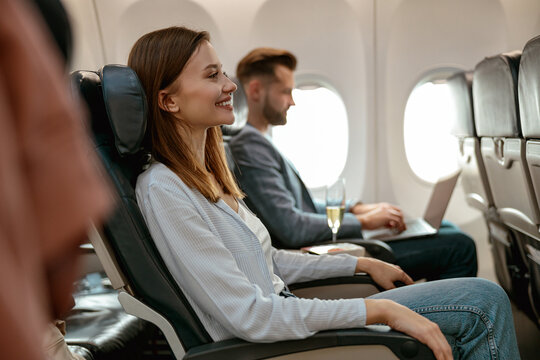 Cheerful woman sitting in passenger chair in airplane