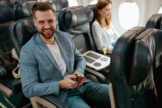 Cheerful Bearded Man Using Mobile Phone In Airplane