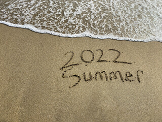 2022 summer is coming , summer writing on the beach , sea water is coming