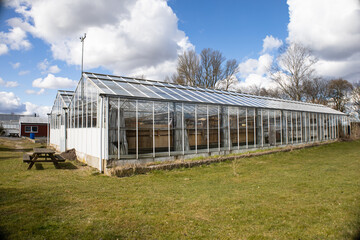 Glass greenhouse in early spring against a cloudy sky. High quality photo