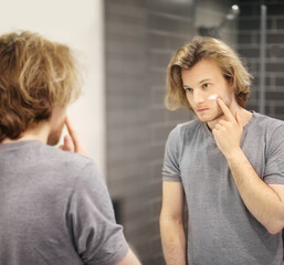 young man looking in the mirror,combing his hair,looking at problems on face.