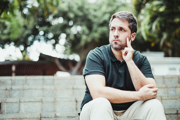 Medium shot of a man sitting on a staircase in a city park with a waiting attitude