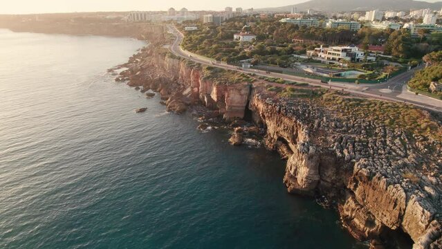 Aerial view of the rocky coast by the sea in Cascais town at sunset, Portugal