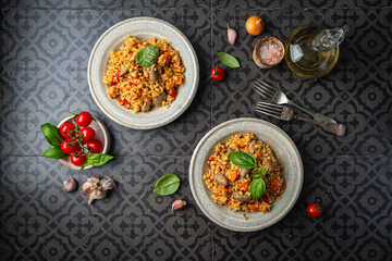 bulgur with chicken hearts and vegetables. Delicious healthy dish on dark background, top view. Bulgur pilaf
