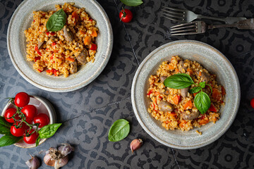 bulgur with chicken hearts and vegetables. Delicious healthy dish on dark background, top view. Bulgur pilaf