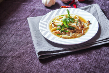 Enoki mushroom stir fry with minced pork served in a white plate on a black velvet table.