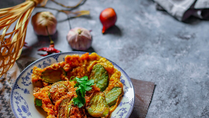 Fried Solanum melongena with Egg in a green dish on the table with garlic, dried chilli