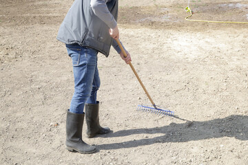 Farmer using a rake to create a fine top layer of soil.
Planting grass. Process of sowing and growing a lawn. Serie of photos.