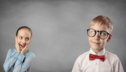 Surprised little presteener girl look on thinking boy. Happy small children isolated on grey studio background