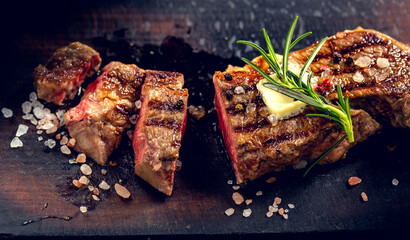 Beef steak with butter seasoned with rosemary, colored pepper and coarse salt. Juicy meat served on an old wooden board.