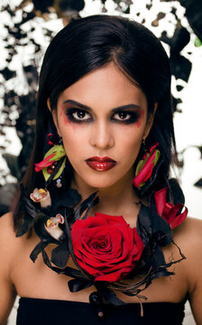 pretty brunette woman with rose jewelry, black and red, bright make up like a vampire closeup red lips