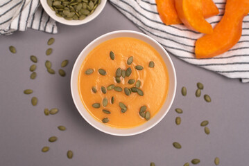A bowl of pumpkin soup in a food composition on a grey background. Healthy food, vegan food. Top view, flat lay. 
