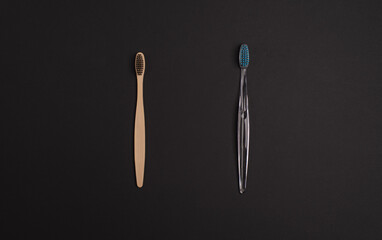 Bamboo and plastic toothbrushes on a dark background. Сonscious consumption concept. Top view, flat lay, space for text. 