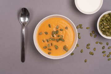 A bowl of pumpkin soup in a food composition on a grey background. Healthy food. Top view. 