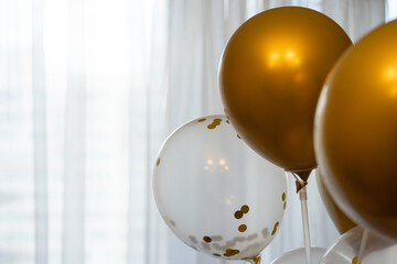 Golden balls on a light background. Festive decoration of the room. Inflatable balls of gold color on a stand. Bright festive background for congratulations.