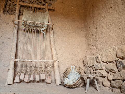 Telar antiguo con un trabajo empezado , palos de madera, cuerdas y contrapesos abajo, contra una pared con piedras, de una casa muy antigua en Soria, Espa&ntilde;a.